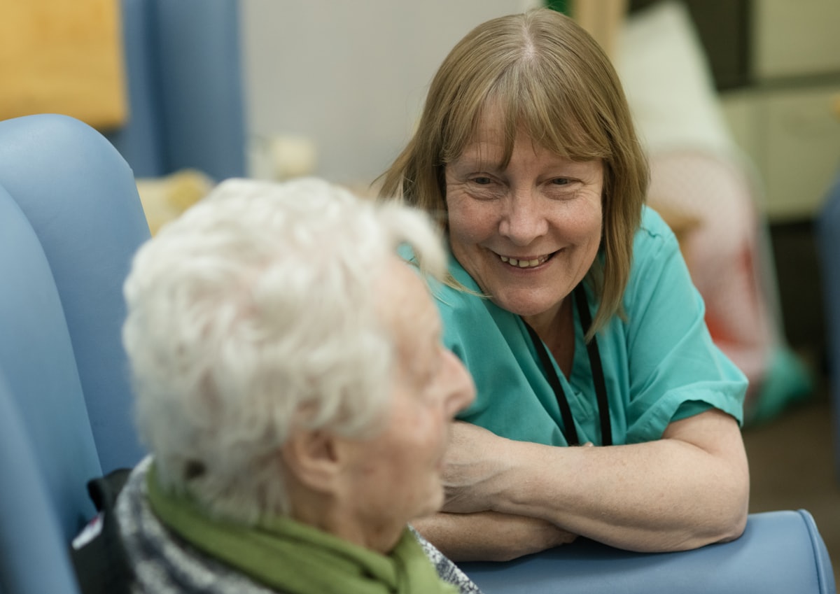 A caregiver leaning in to talk with a resident